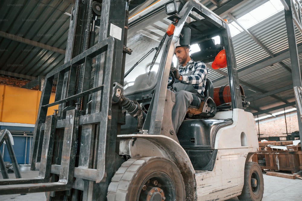 Forklift driver. Factory male worker in uniform is indoors.