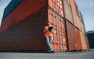 Digital tablet in hands. Male worker is on the location with containers.