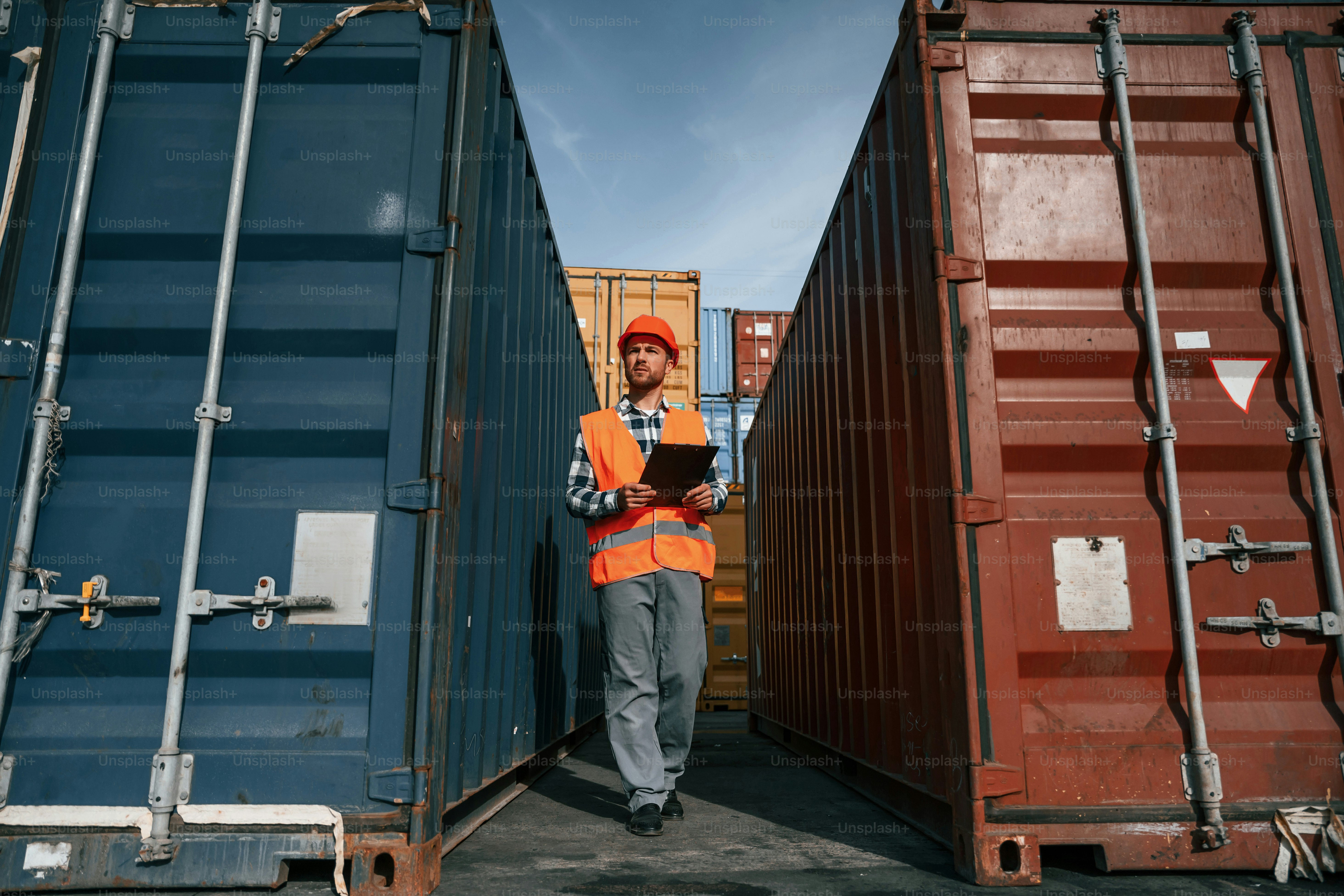 Männlicher Arbeiter ist mit Containern vor Ort. Mit digitalem Tablet.