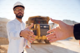 Giving a hand. Making a deal. Man in uniform is working in the quarry at daytime.