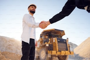 Quarry worker making a deal with colleague. Shaking hands.