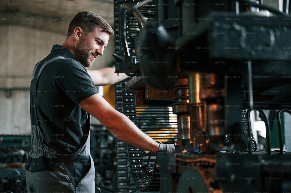 Dispositivo per la lavorazione dei metalli. L'uomo in uniforme è in postazione di lavoro sviluppando dettagli della tecnica agricola.