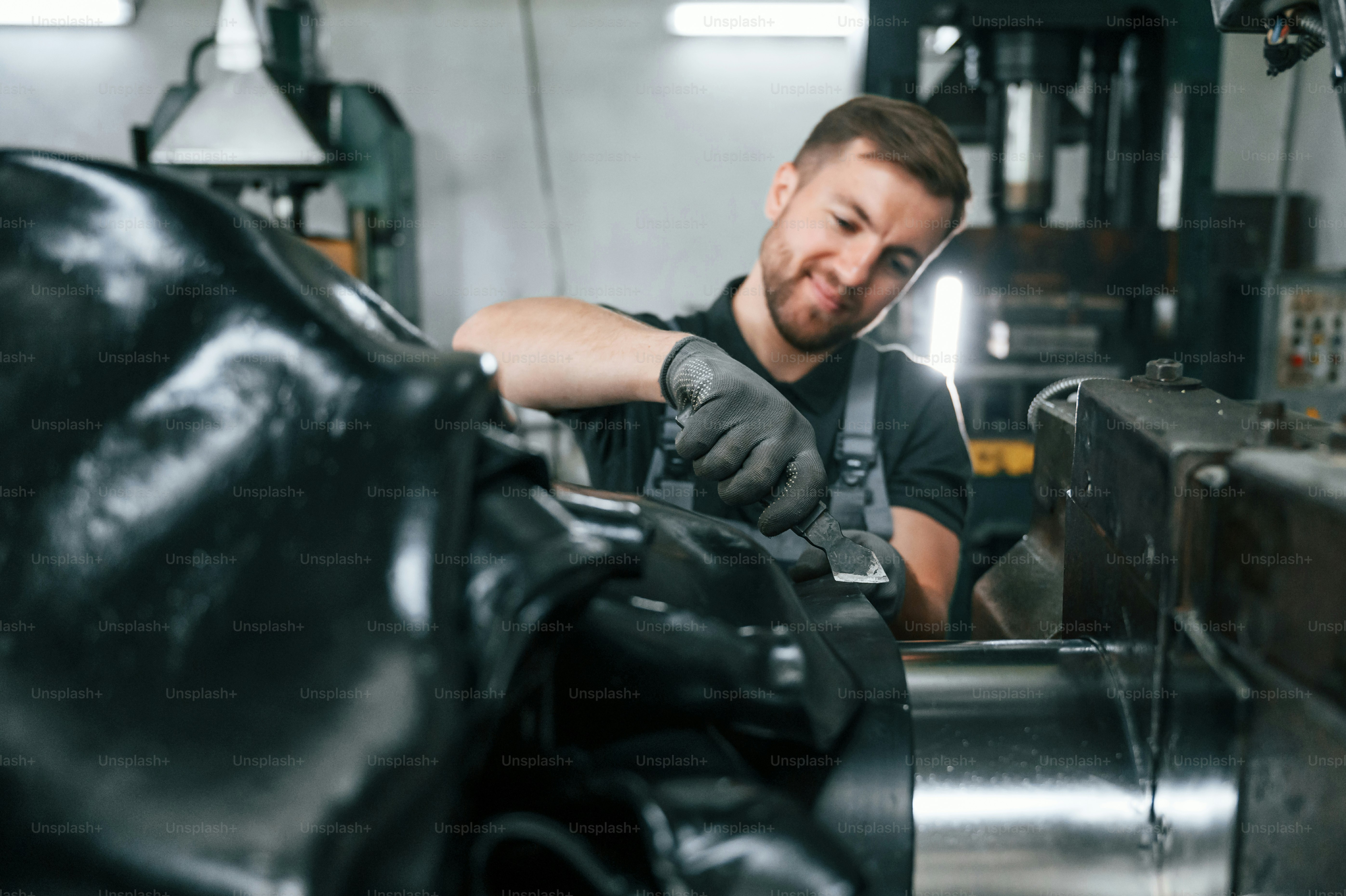 Limpe as peças. Homem de uniforme está em estação de trabalho desenvolvendo detalhes da técnica agrícola.