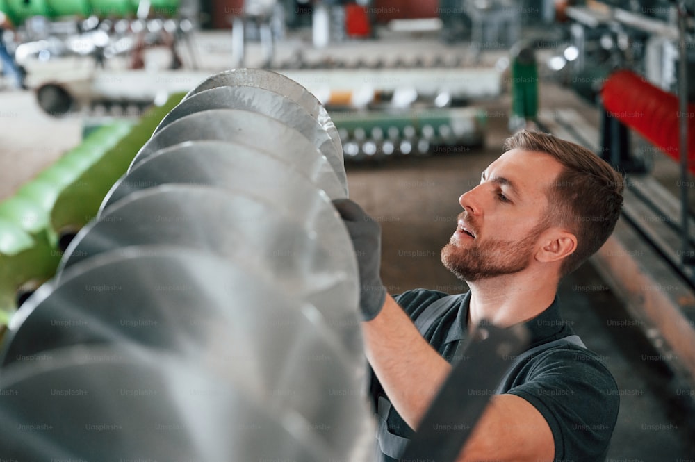 Checking slicing parts. Man in uniform is in workstation developing details of agriculture technique.