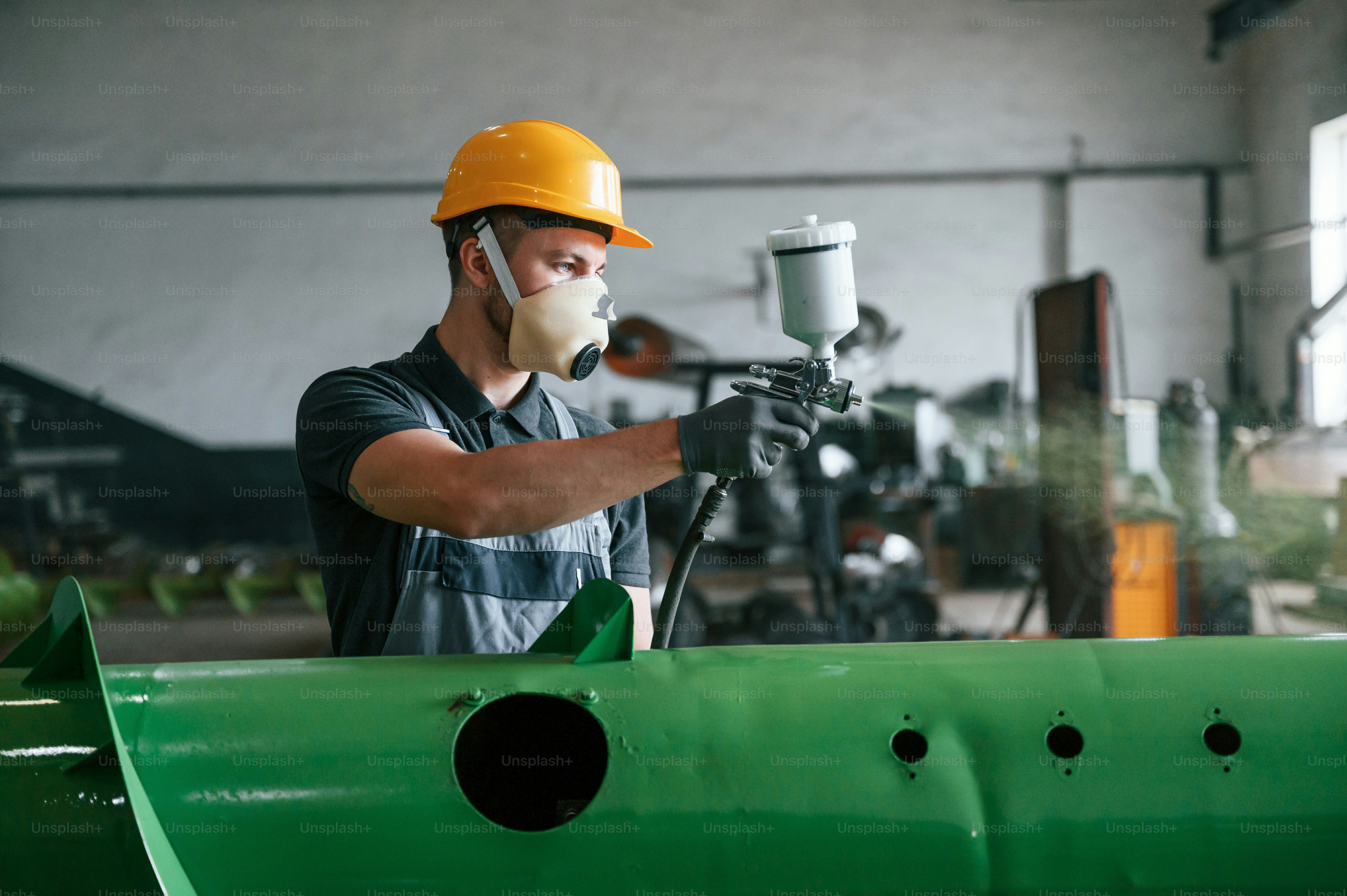 Painting details. Man in uniform is in workstation developing details of agriculture technique.