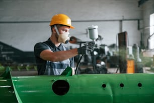 Painting details. Man in uniform is in workstation developing details of agriculture technique.