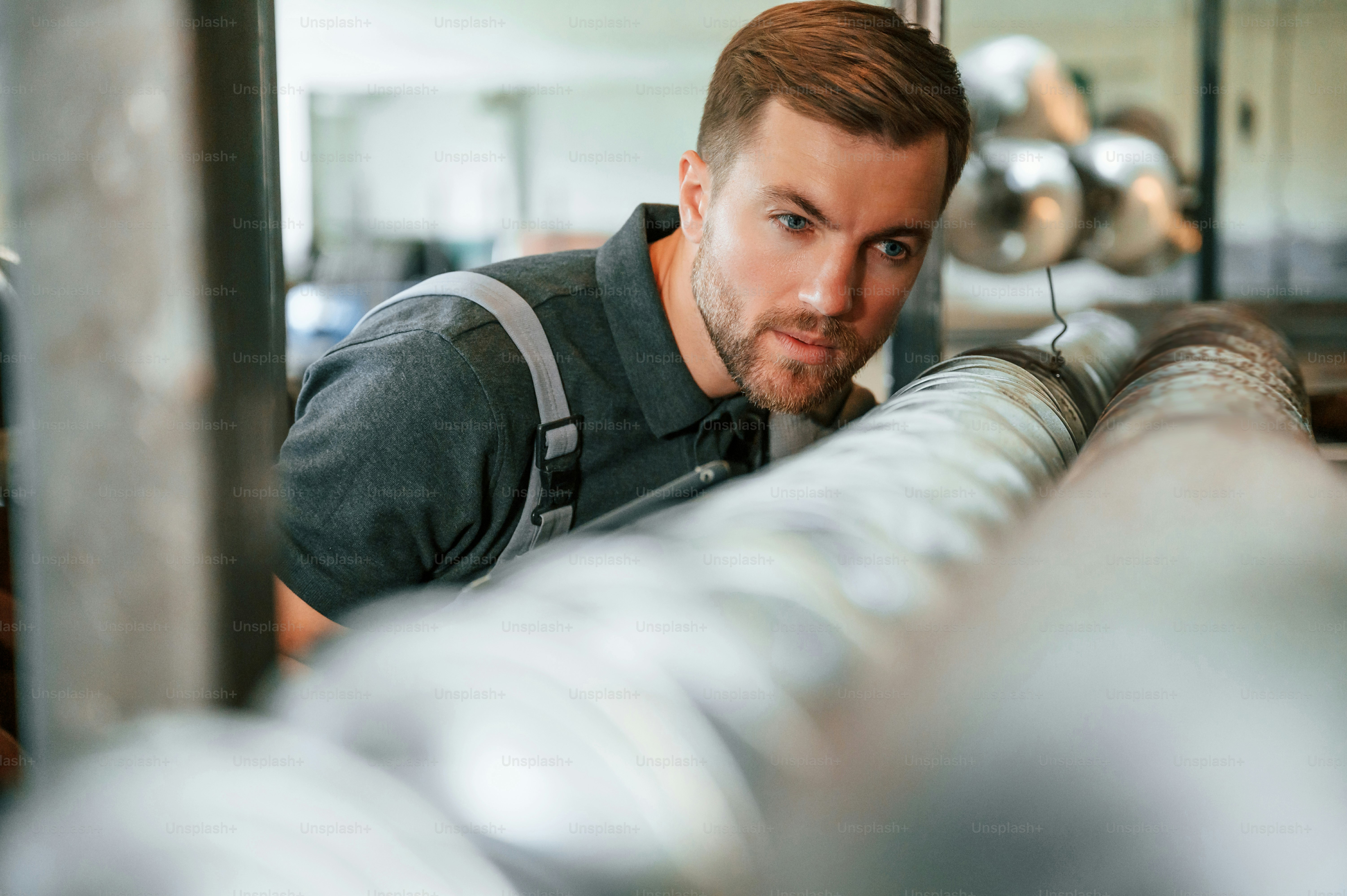 Medição do comprimento de peças metálicas. Homem de uniforme está em estação de trabalho desenvolvendo detalhes da técnica agrícola.
