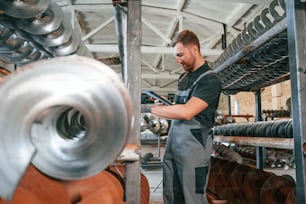 Holding tablet. Man in uniform is in workstation developing details of agriculture technique.