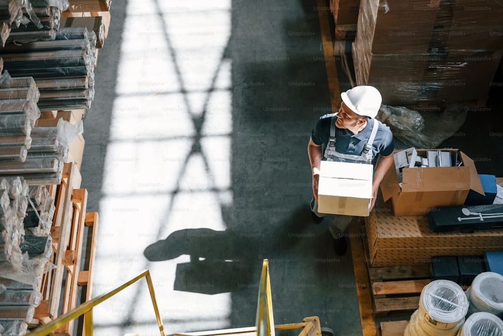 Top view of employee in uniform that is working in the storage at daytime.