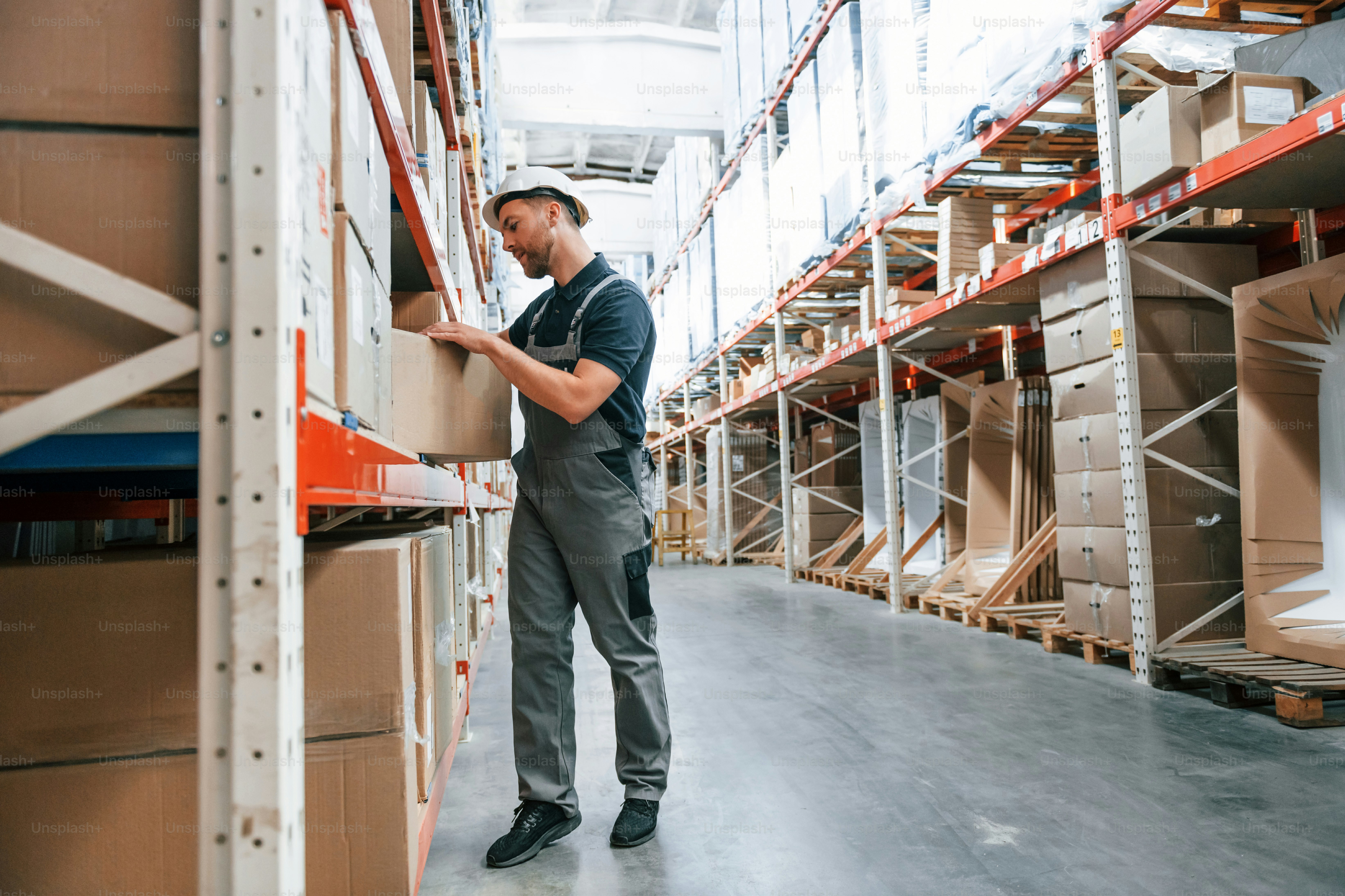 Taking out the box. Employee in uniform is working in the storage at daytime.