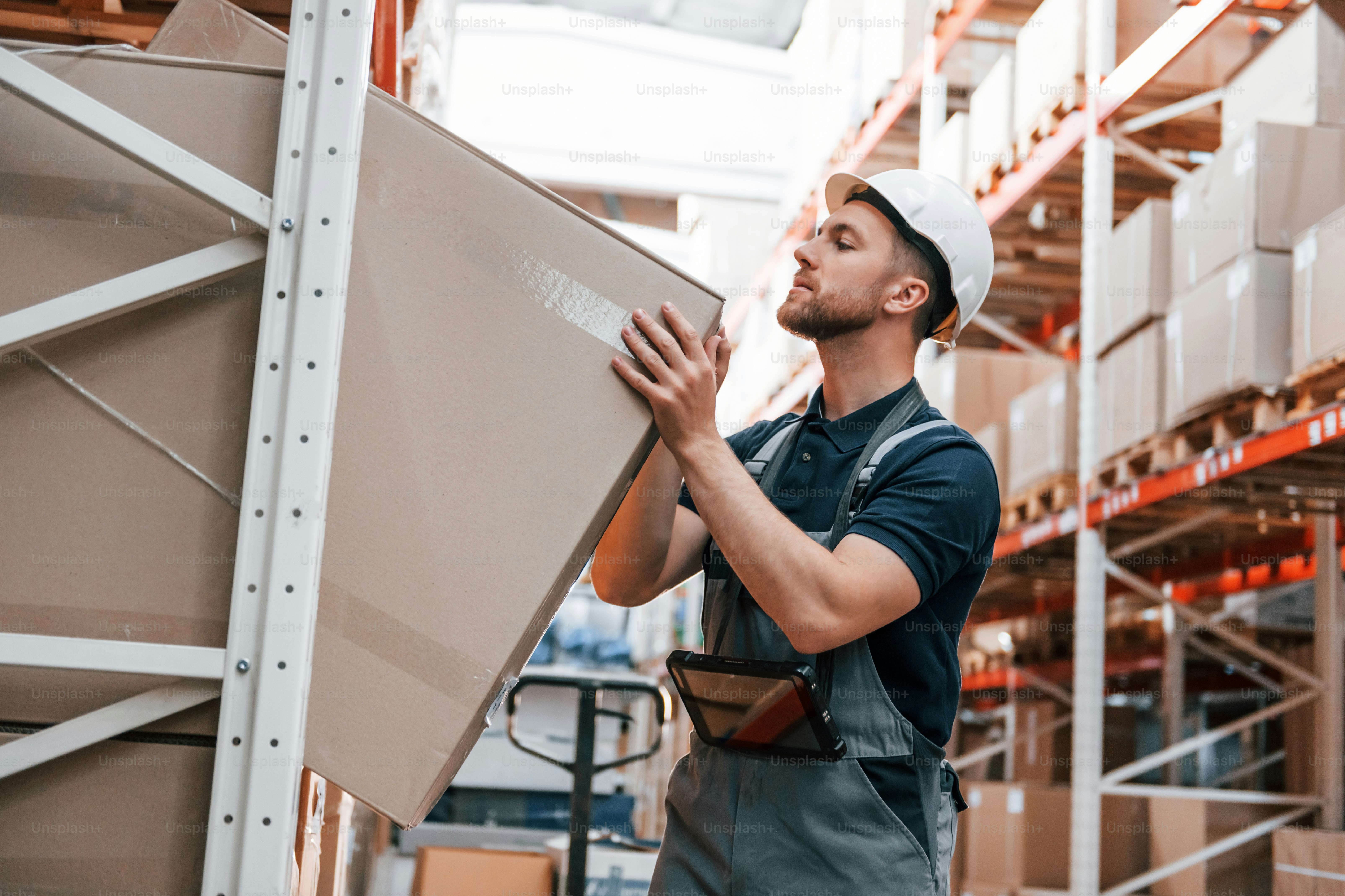 Taking out the box. Employee in uniform is working in the storage at daytime.