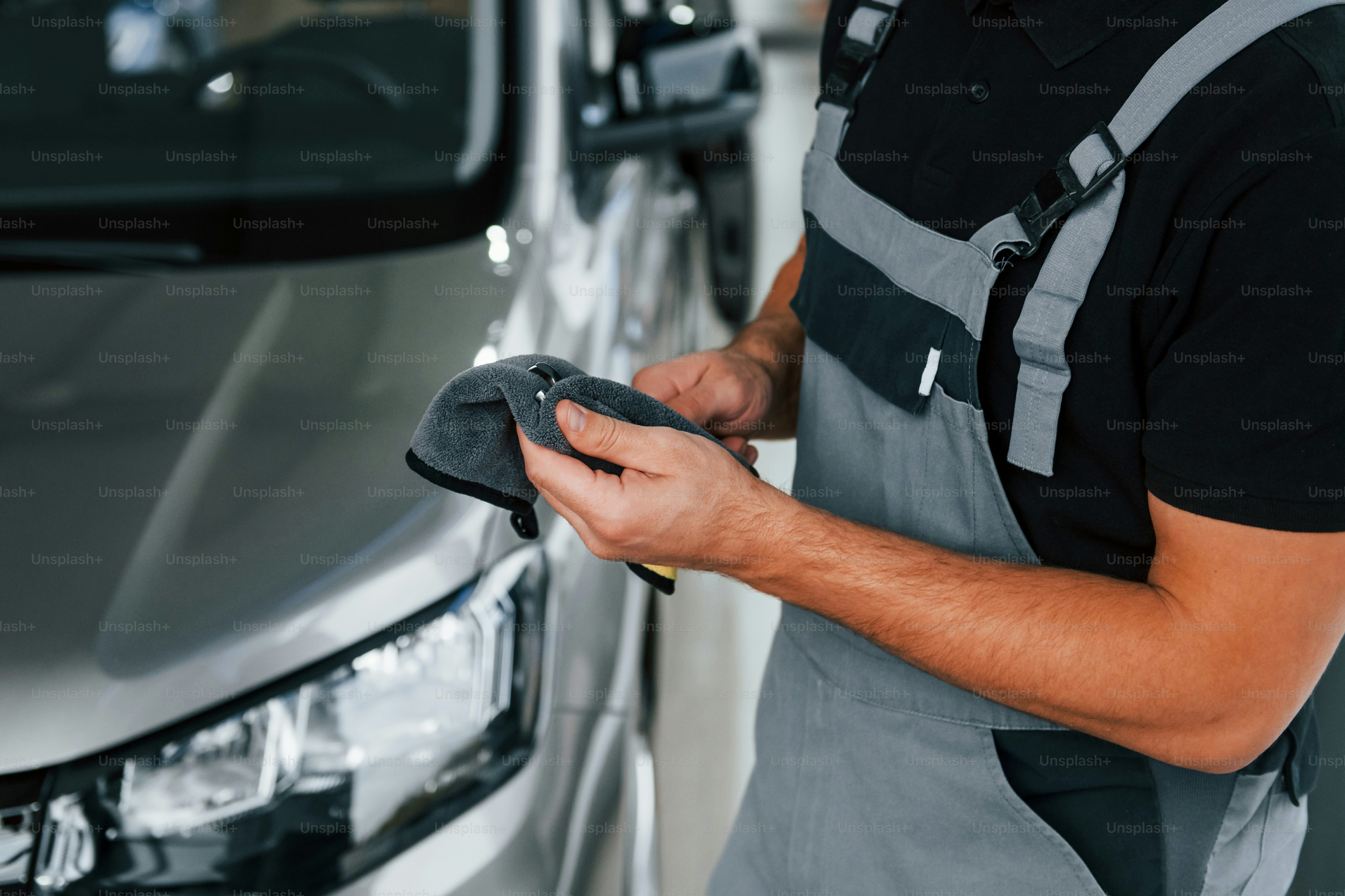 Tools in hands. Man in uniform is working in the autosalon at daytime.