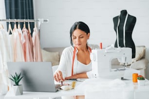 Professional sewing machine. Seamstress is in her office that is with different clothes.