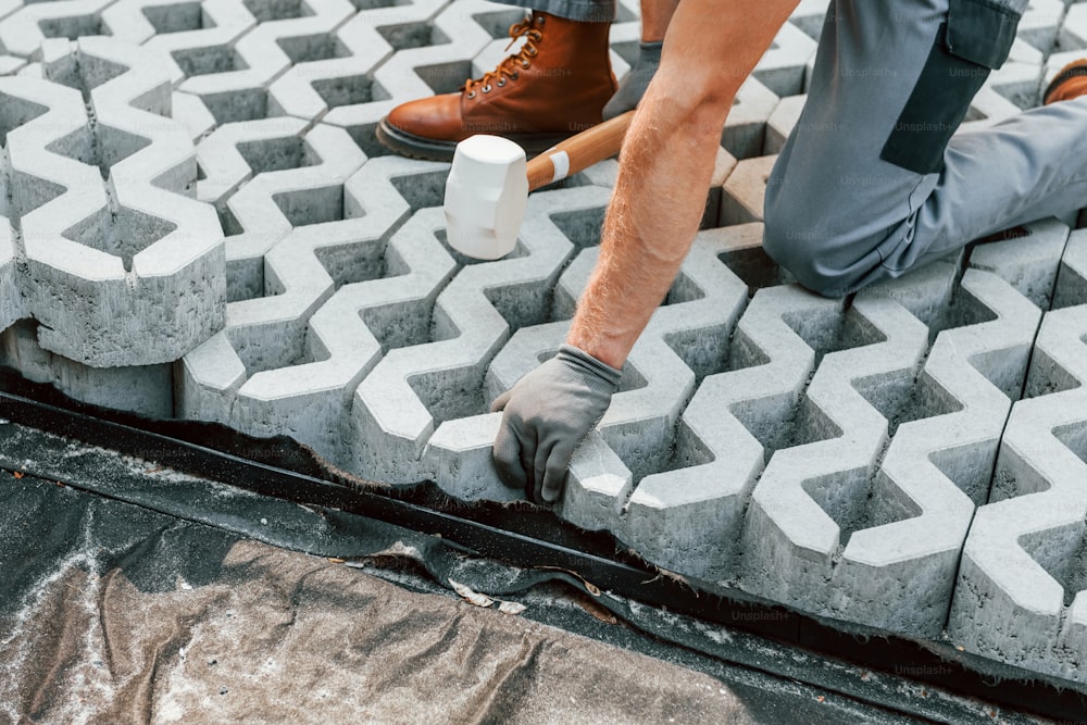 Assis à l’extérieur. Jeune homme travaillant en uniforme dans la construction pendant la journée.