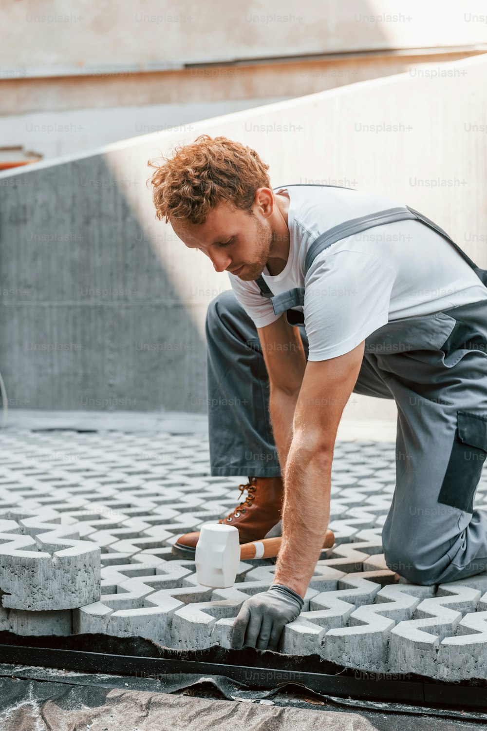 Sitting outdoors. Young man working in uniform at construction at daytime.