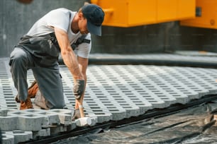 Job outdoors. Young man working in uniform at construction at daytime.