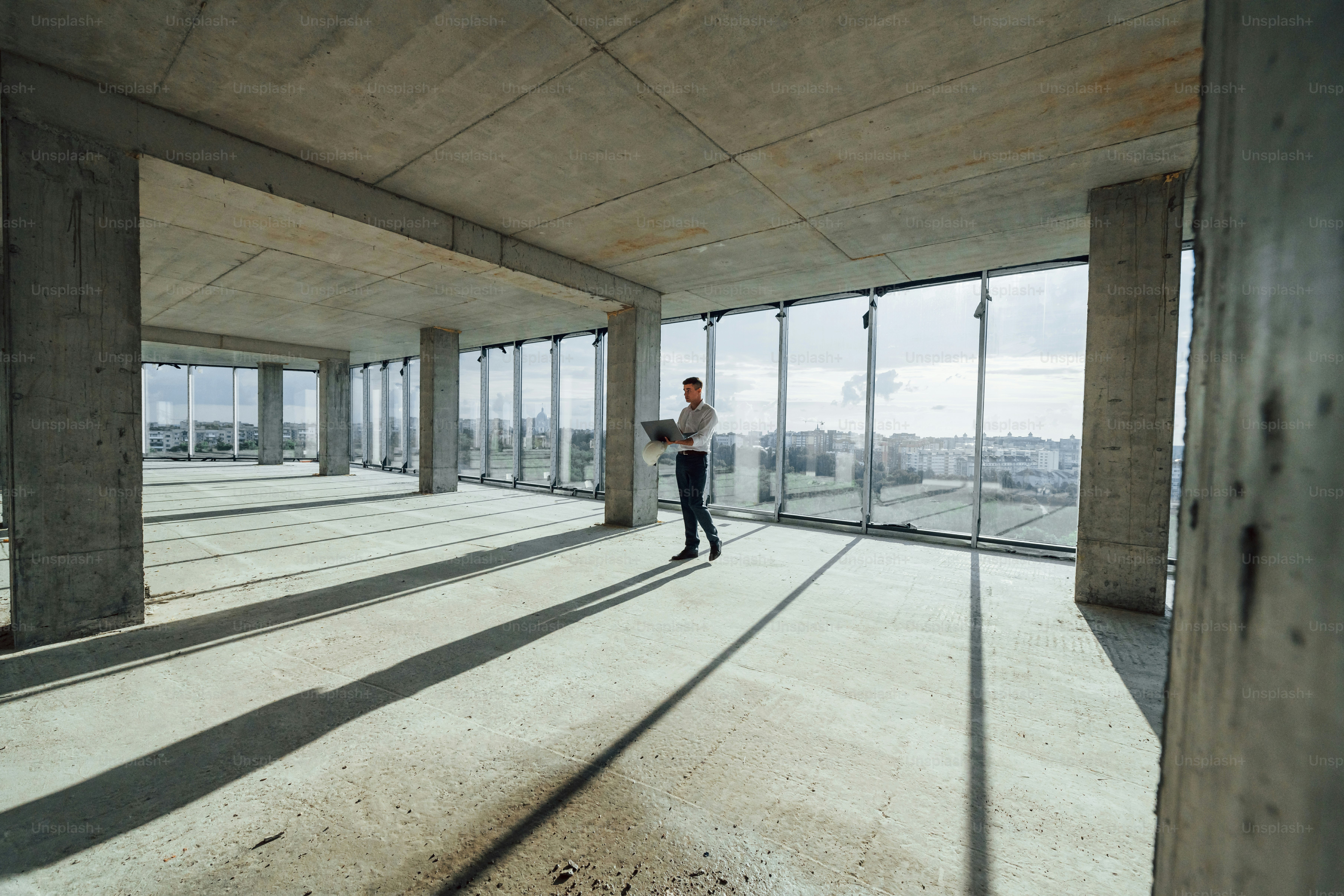 La belle lumière du soleil passe par une grande fenêtre. Un jeune homme en tenue de soirée travaille à l’intérieur sur la construction.