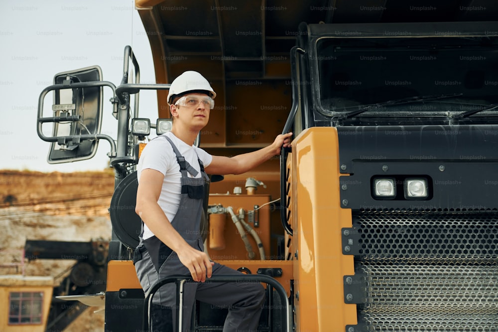 Quality vehicle. Worker in professional uniform is on the borrow pit at daytime.