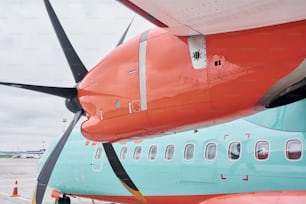 Color naranja y azul. Aviones turbohélice estacionados en la pista durante el día.