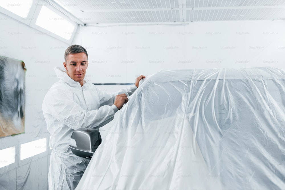 制服を着た白人の自動車修理工はガレージで働いています。