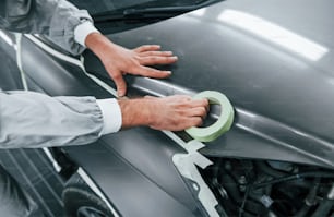 Detailed work. Caucasian automobile repairman in uniform have job in garage.