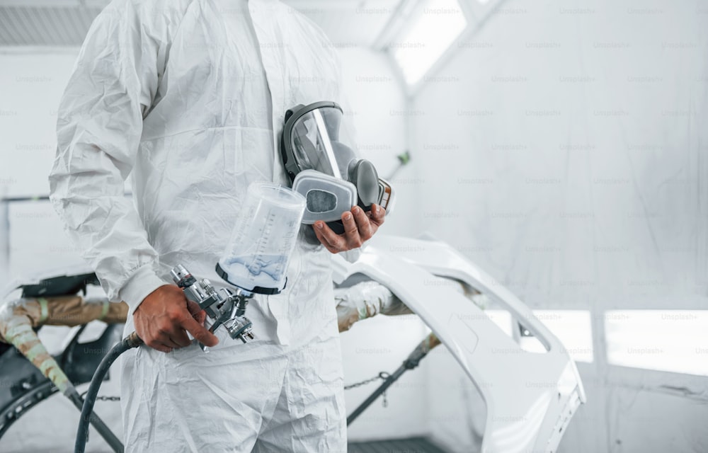 Close up view. Caucasian automobile repairman in uniform works in garage.