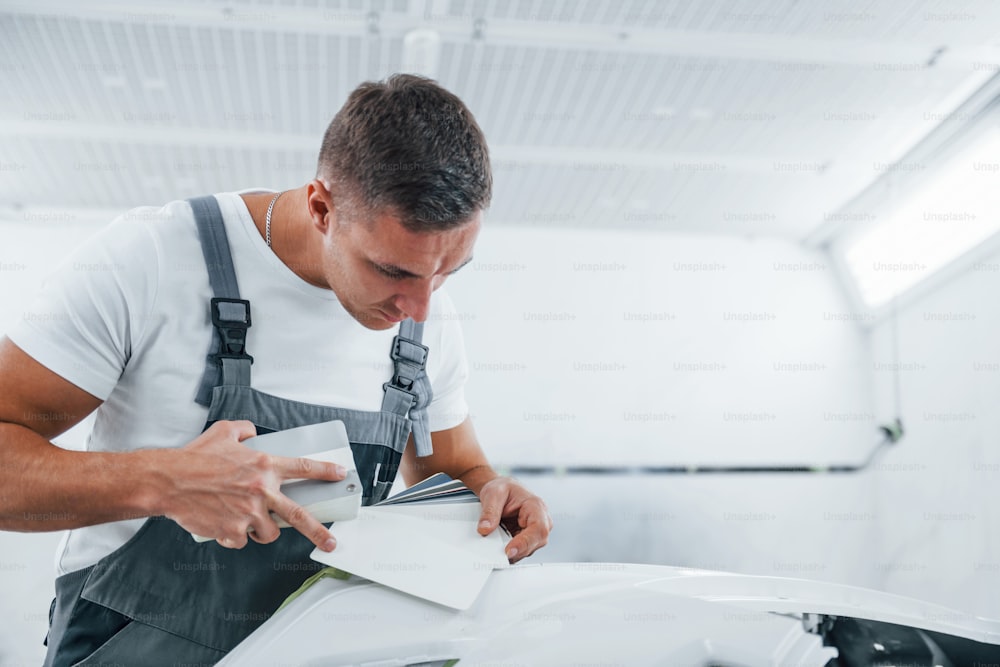 Detailed work. Caucasian automobile repairman in uniform have job in garage.