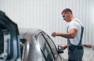 Réparateur automobile caucasien en uniforme travaille dans un garage.