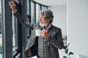 Empresário no escritório. Homem moderno elegante sênior com cabelos grisalhos e barba dentro de casa.