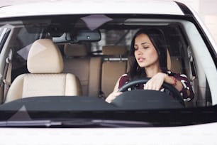 Beautiful young brunette inside of modern automobile. Riding car.