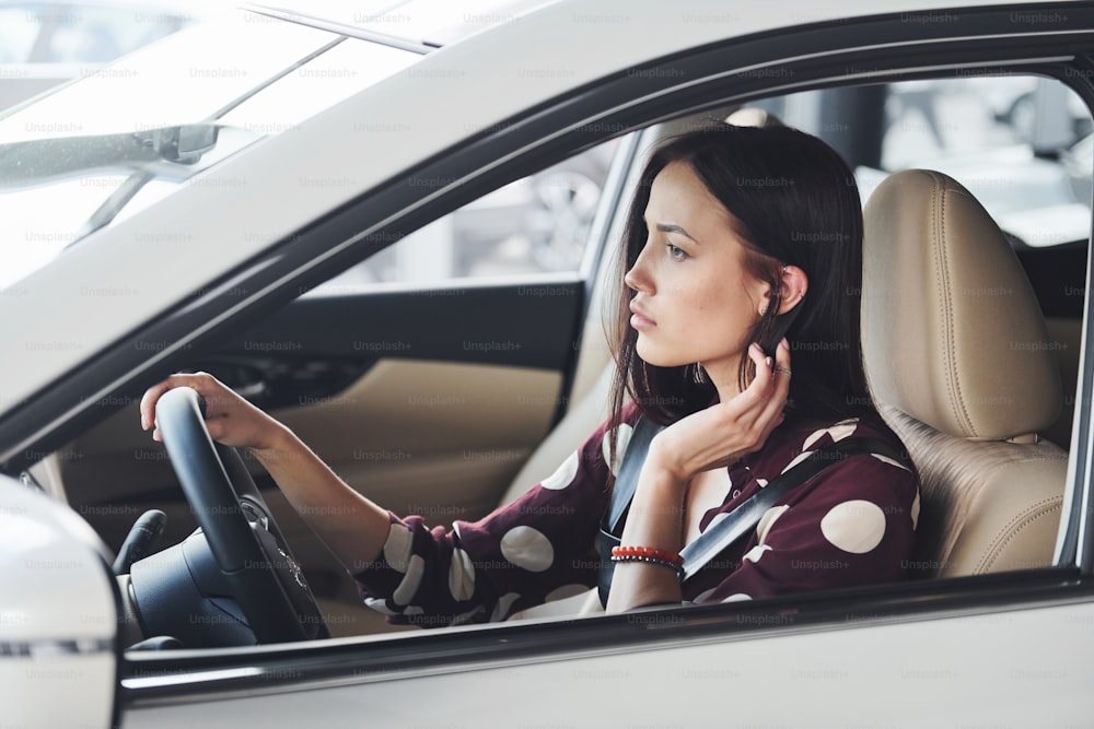 Side view of beautiful young brunette that inside of modern automobile. Riding car.