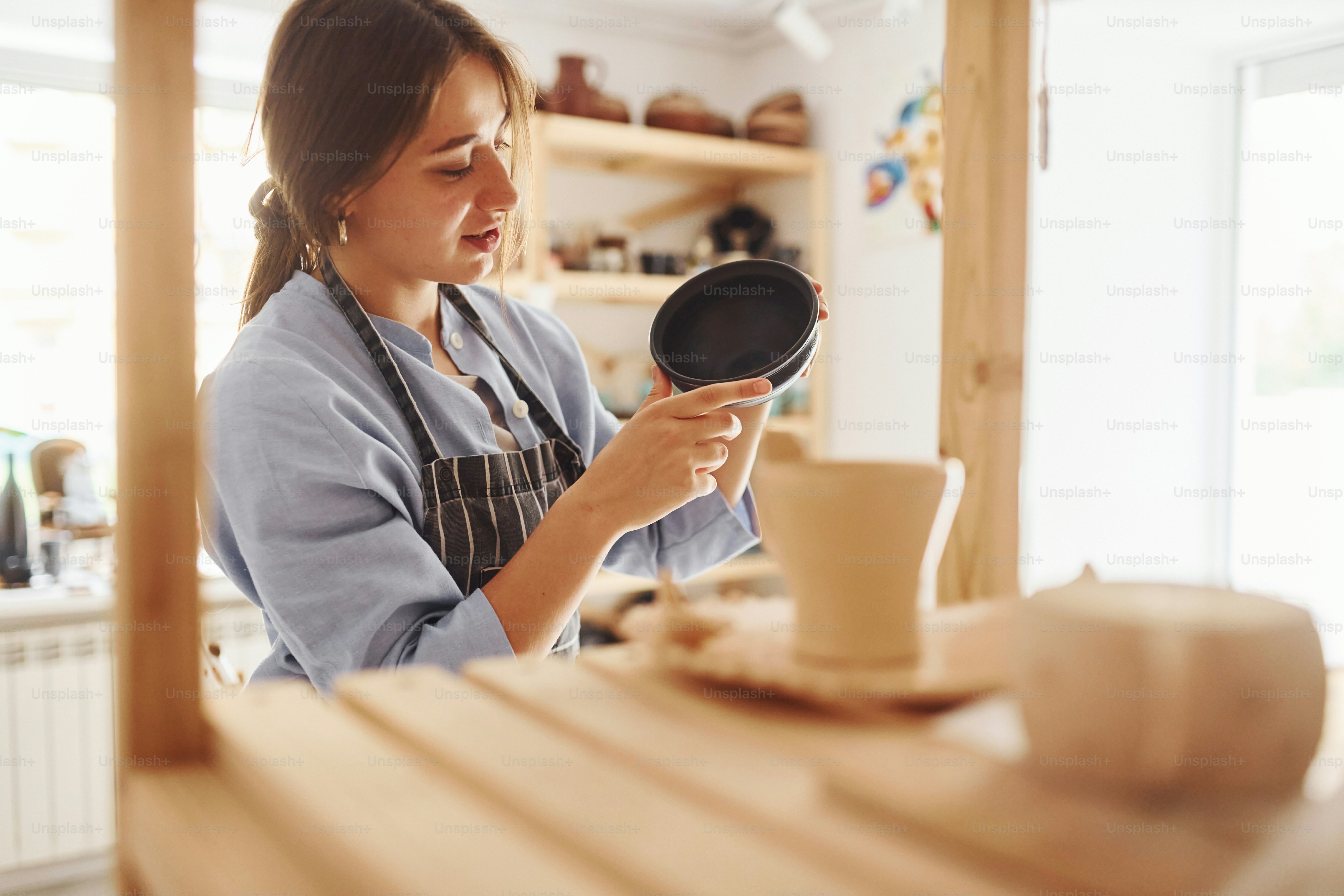Job is done. Young female ceramist indoors with finished handmade clay product. Conception of