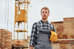 Hard hat and case in hands. Construction worker in uniform and safety equipment have job on building.