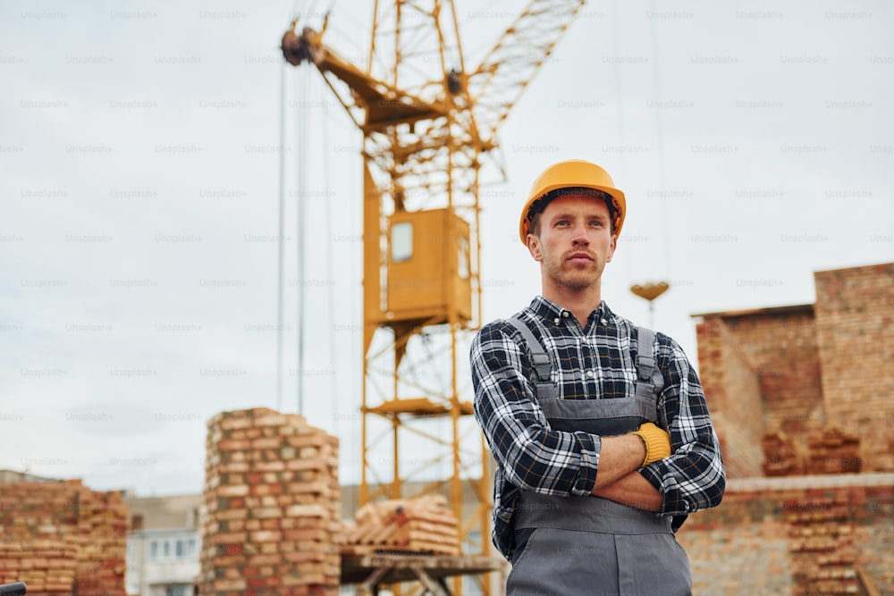 Les bras croisés. Les travailleurs de la construction en uniforme et en équipement de sécurité ont un emploi sur le bâtiment.