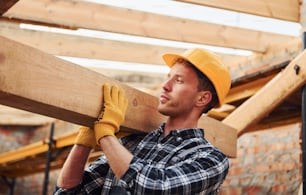 Transport von Holzbrettern. Bauarbeiter in Uniform und Sicherheitsausrüstung haben Arbeit am Gebäude.
