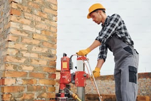 Utilise une perceuse de mélange. Les travailleurs de la construction en uniforme et en équipement de sécurité ont un emploi sur le bâtiment.