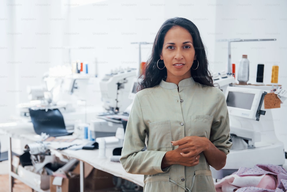 Beautiful female worker is in the sewing factory at daytime.