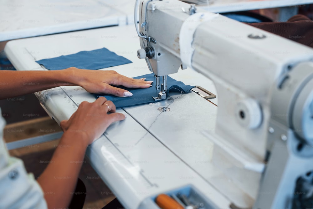 Vista detalhada da mulher costureira costura roupas na máquina de costura na fábrica.