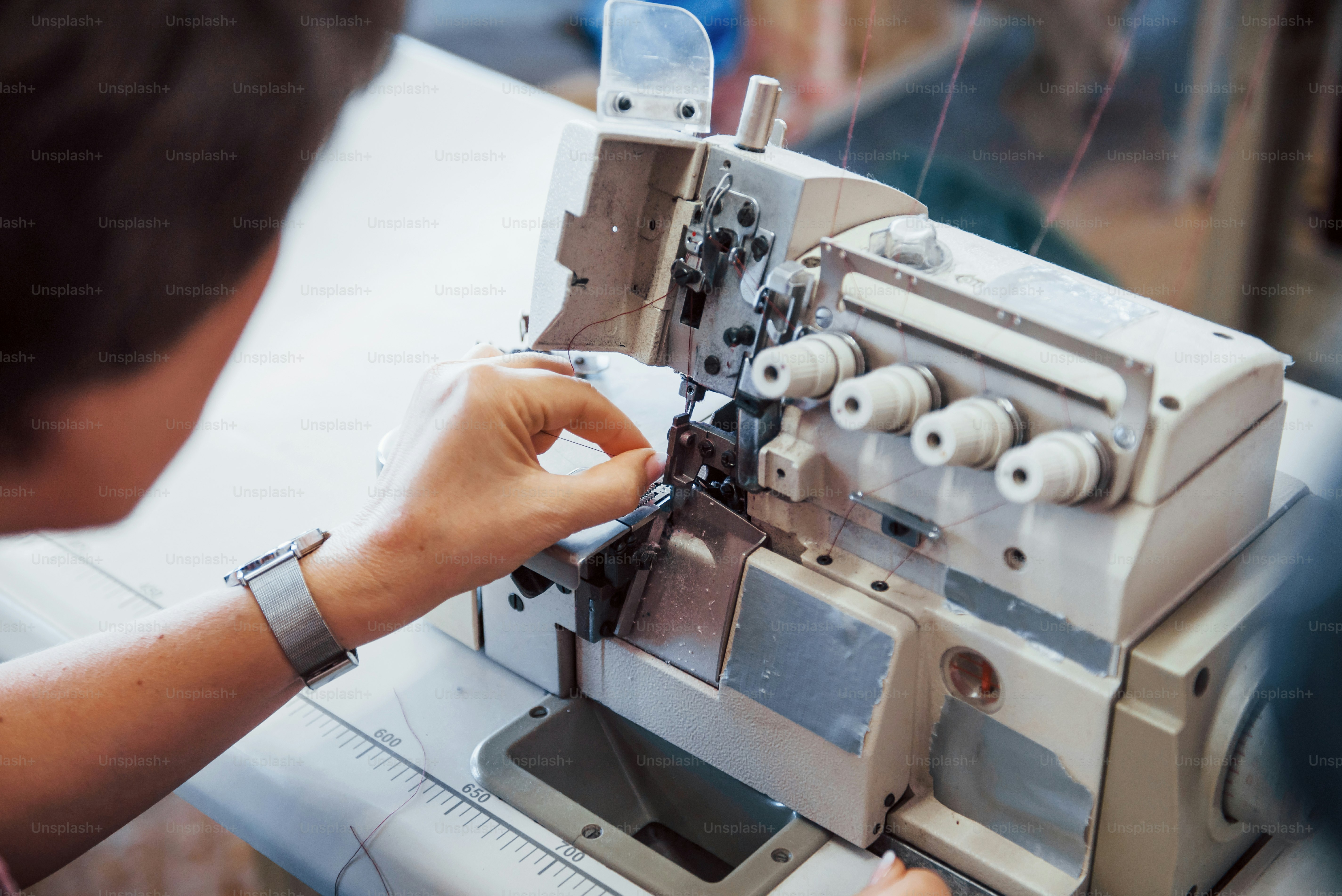 Dressmaker woman sews clothes on sewing machine in factory.