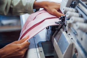 Vue détaillée d’une couturière coudre des vêtements sur une machine à coudre en usine.