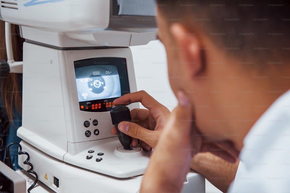 Oculist teste la vision du patient en utilisant une machine moderne spéciale.
