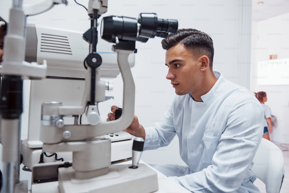 Oculist prueba la visión del paciente mediante el uso de una máquina moderna especial.