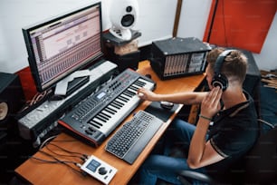 ヘッドフォンのサウンドエンジニアがスタジオの屋内で音楽を操作およびミキシングします。