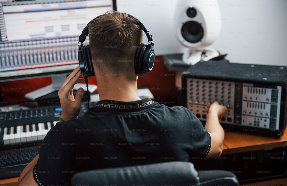Ingeniero de sonido en auriculares trabajando y mezclando música en interiores en el estudio.