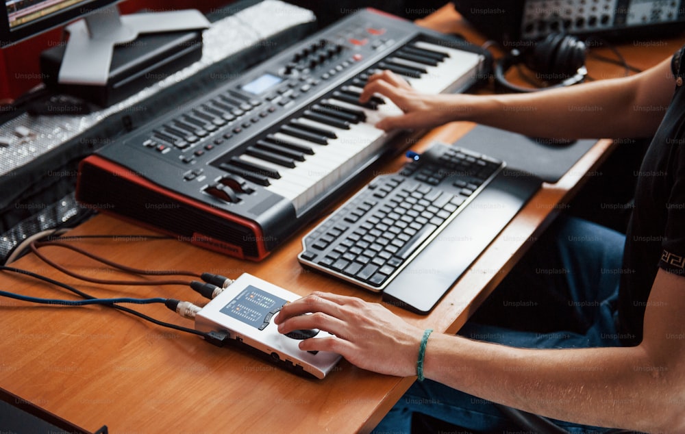 Tocando teclado midi. Engenheiro de som trabalhando e mixando música dentro de casa no estúdio.