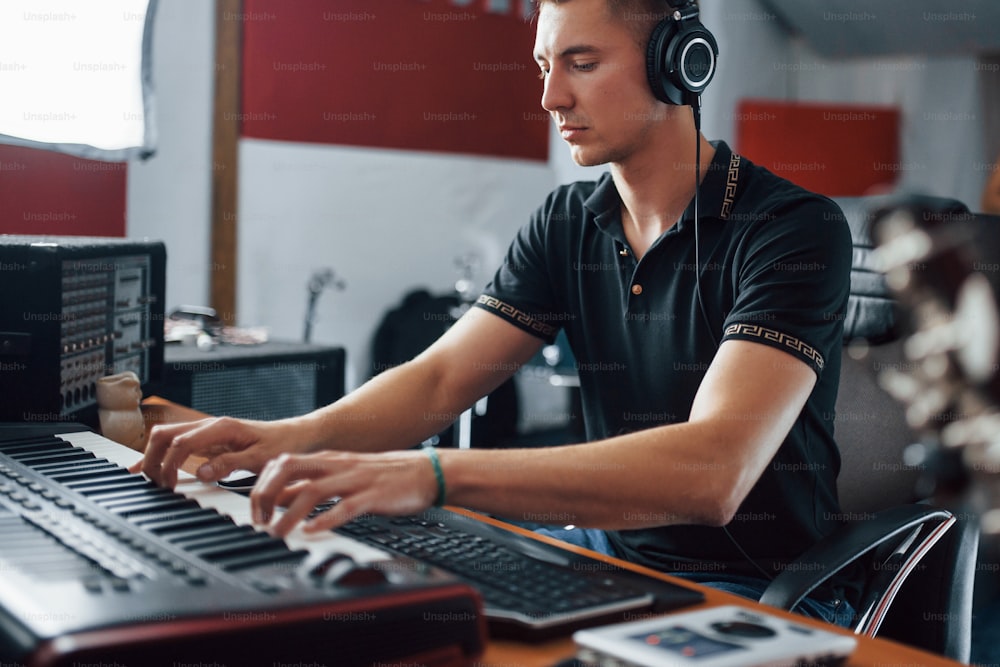 헤드폰을 착용한 사운드 엔지니어는 스튜디오에서 실내에서 음악을 작업하고 믹싱합니다.