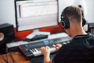Engenheiro de som em fones de ouvido trabalhando e mixando músicas dentro de casa no estúdio.
