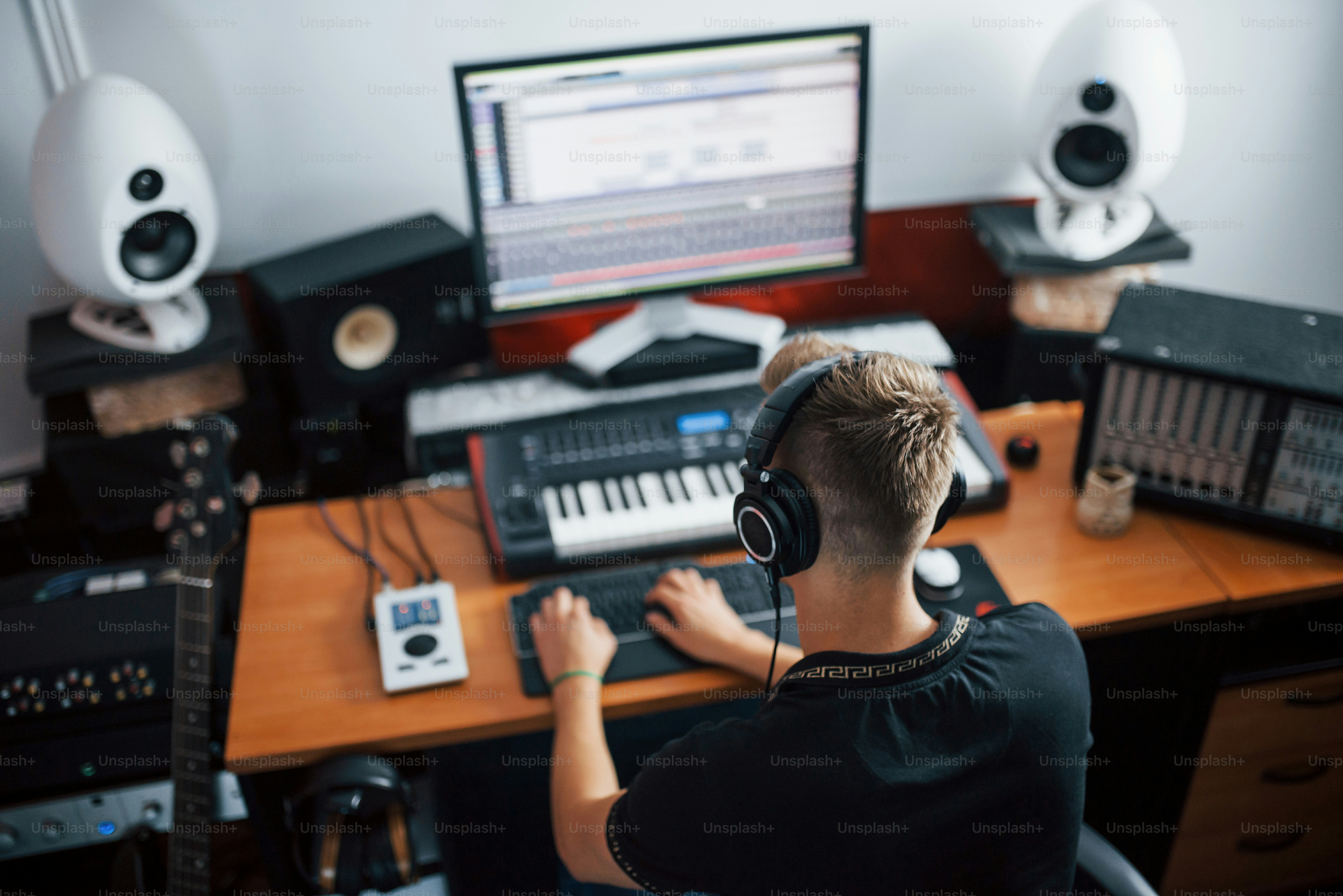 Playing midi keyboard. Sound engineer working and mixing music indoors ...