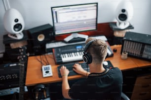 Tontechniker mit Kopfhörern, der drinnen im Studio arbeitet und Musik mischt.