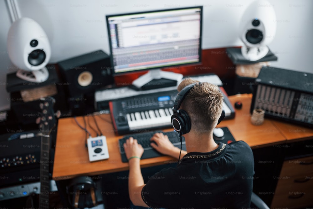 Tecnico del suono in cuffia che lavora e mixa musica al chiuso in studio.